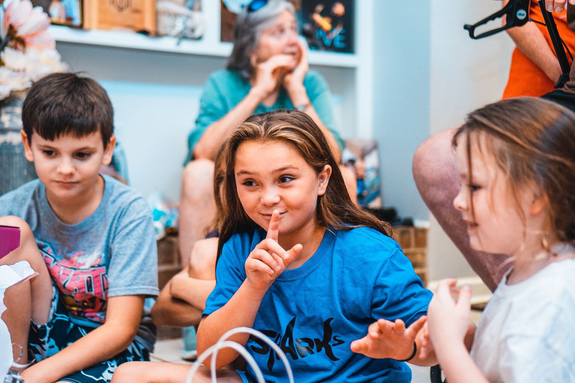 A group of children are sitting on the floor in a living room.