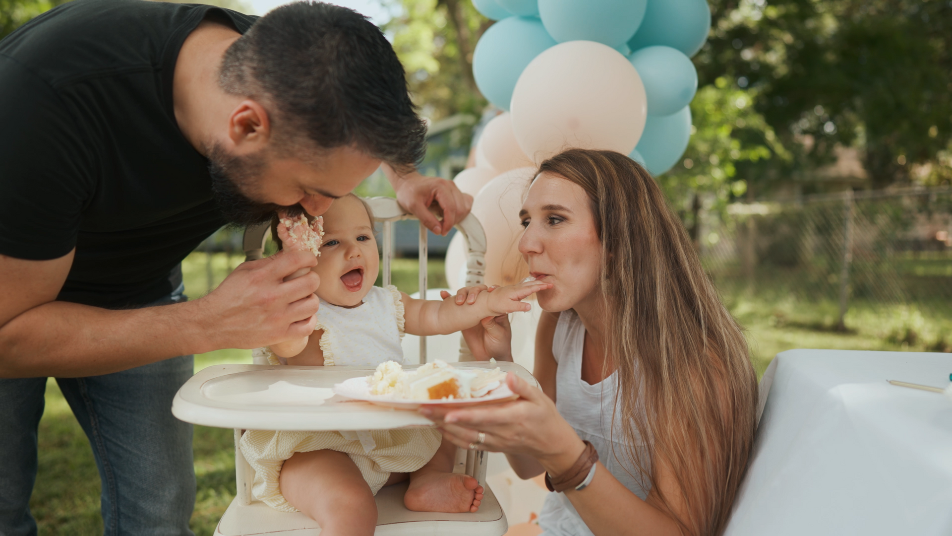 A man and woman are feeding a baby in a high chair.