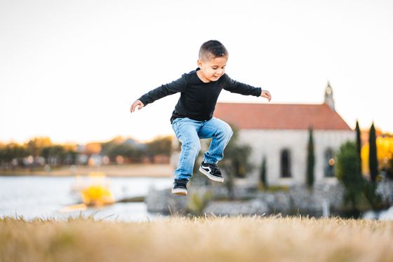 A young boy is jumping in the air in front of a church.