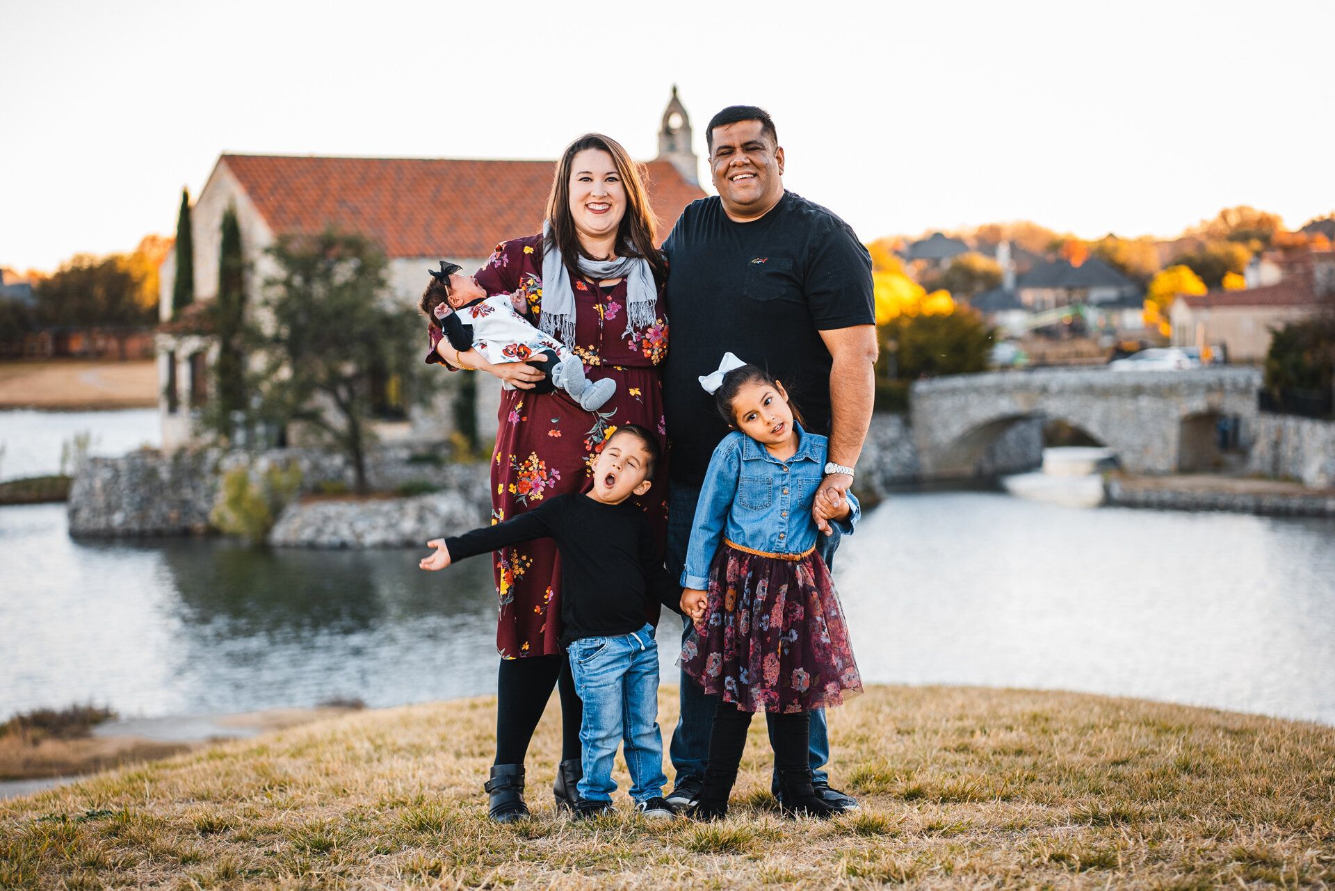 A family is posing for a picture in front of a lake.