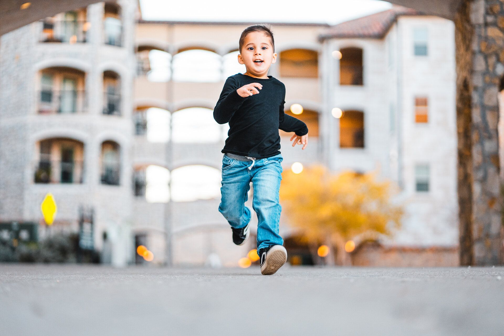 A young boy is running down a street in front of a building.