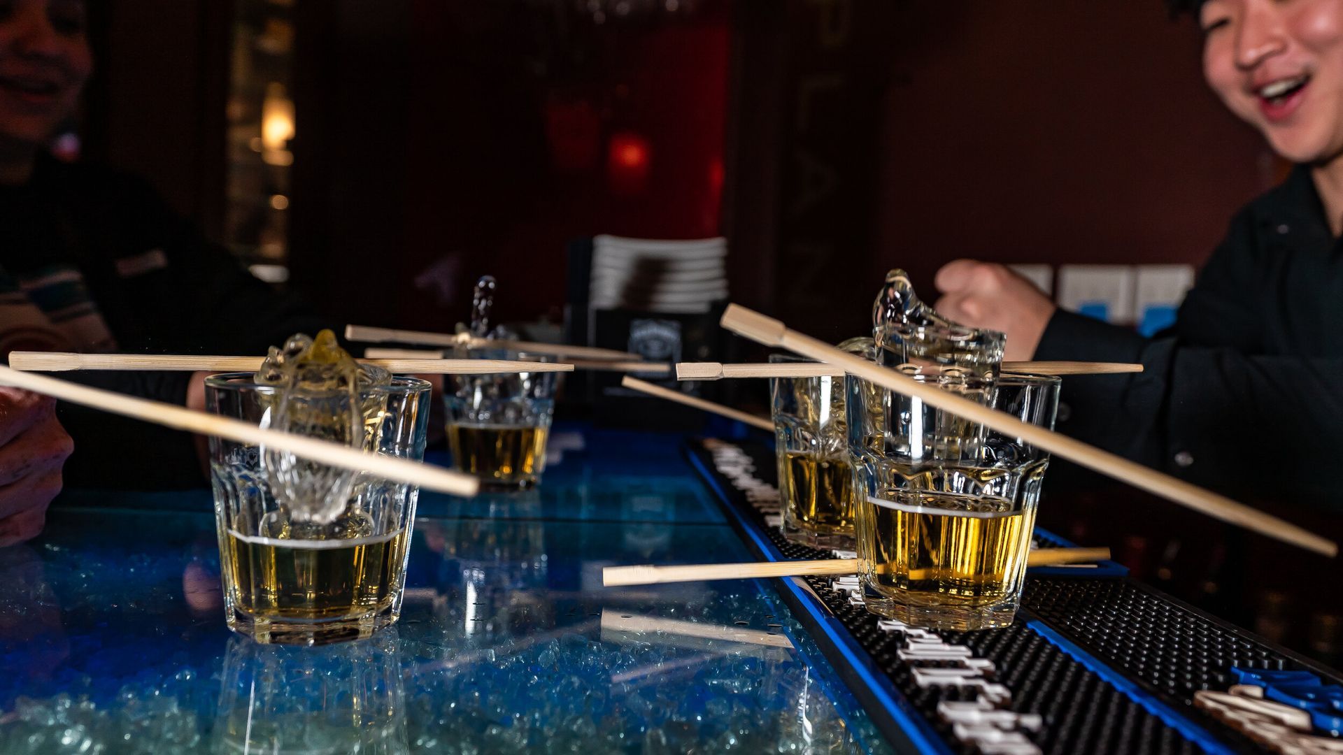 A bar with a lot of shot glasses and chopsticks on it.