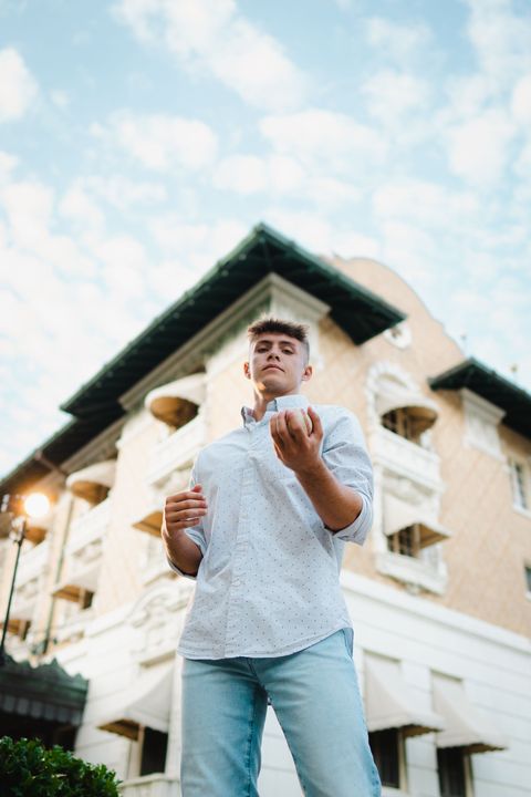 A man in a white shirt and jeans is standing in front of a building.