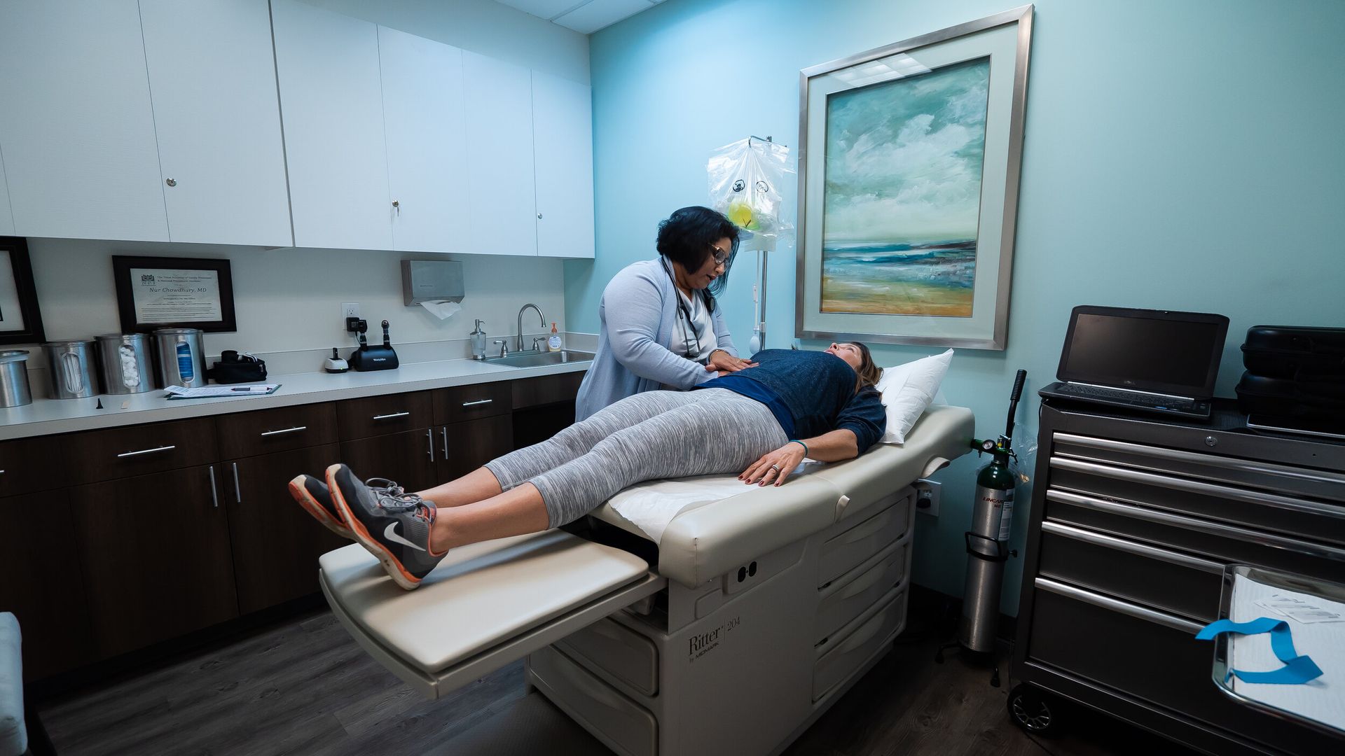 A woman is laying on a bed while a doctor examines her.