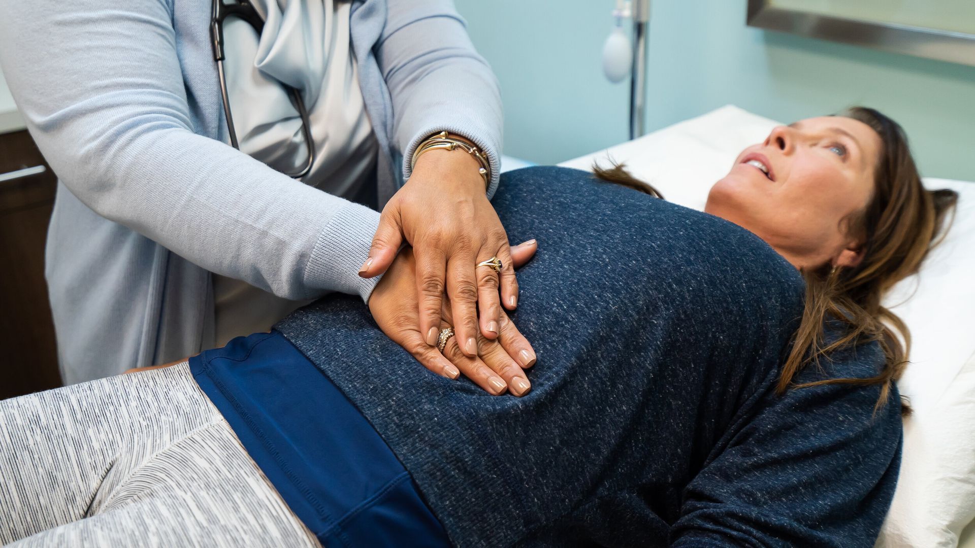 A woman is laying on a bed with her hands on her stomach.