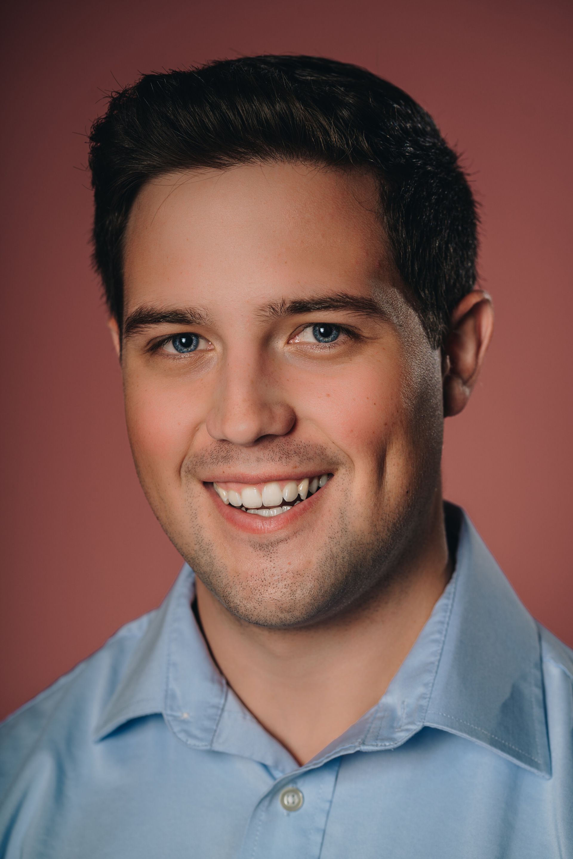 A man in a blue shirt is smiling for the camera.