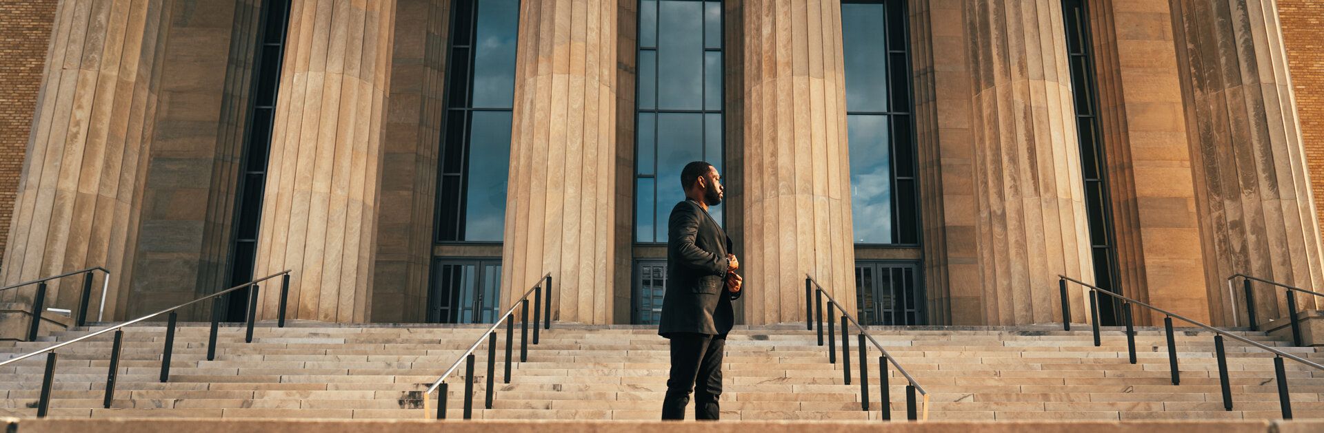 A man in a suit is standing on the steps of a building.