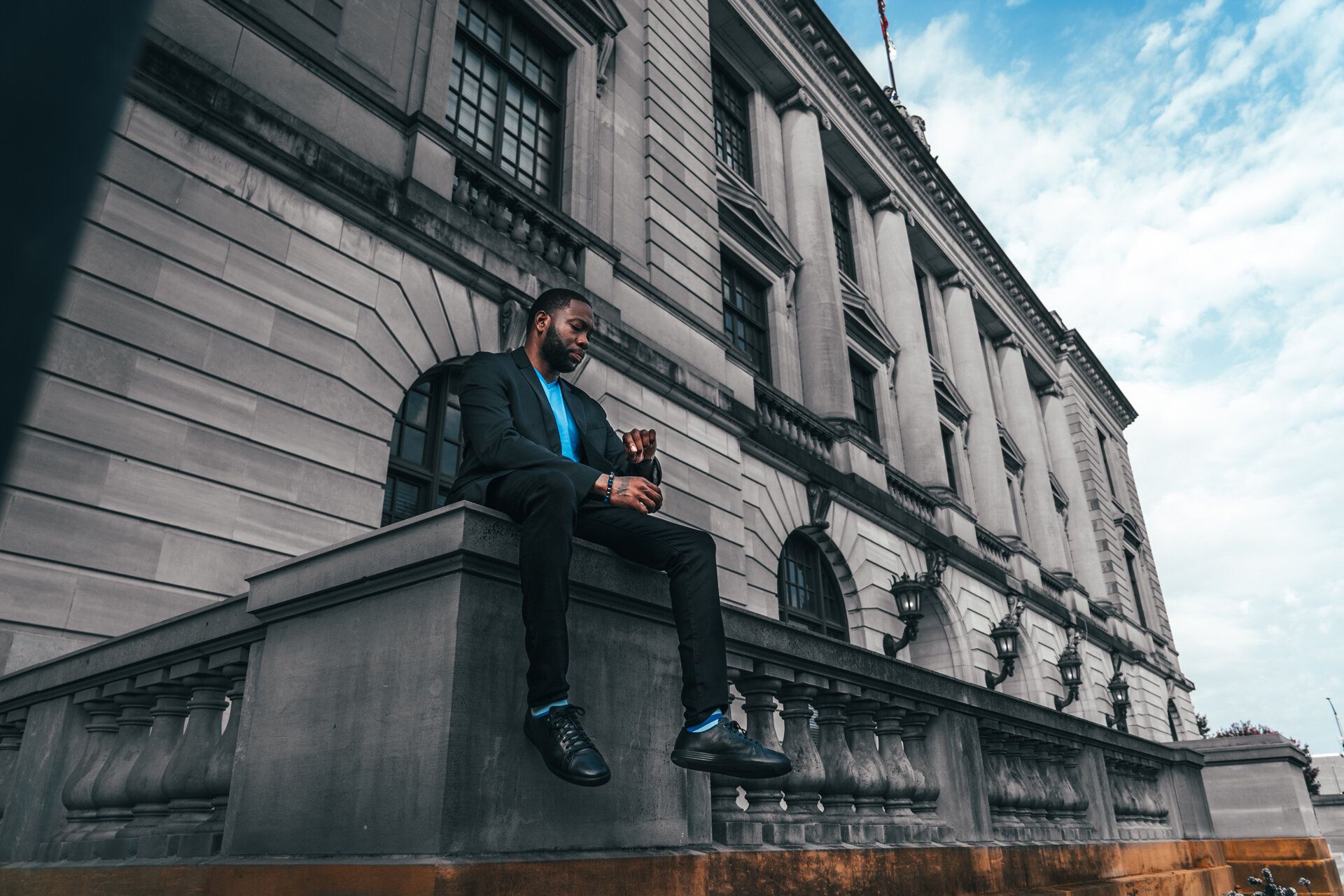 A man in a suit is sitting on the steps of a building.