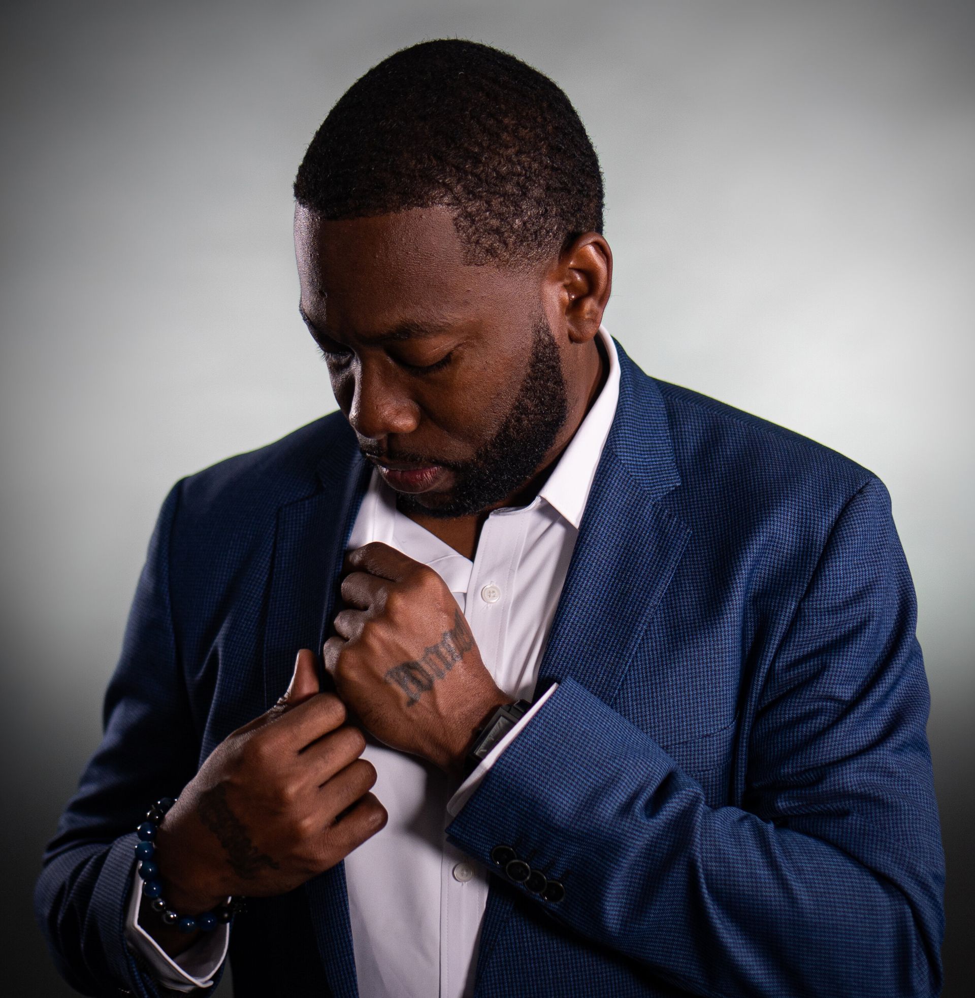 A man in a blue suit has a tattoo on his hand