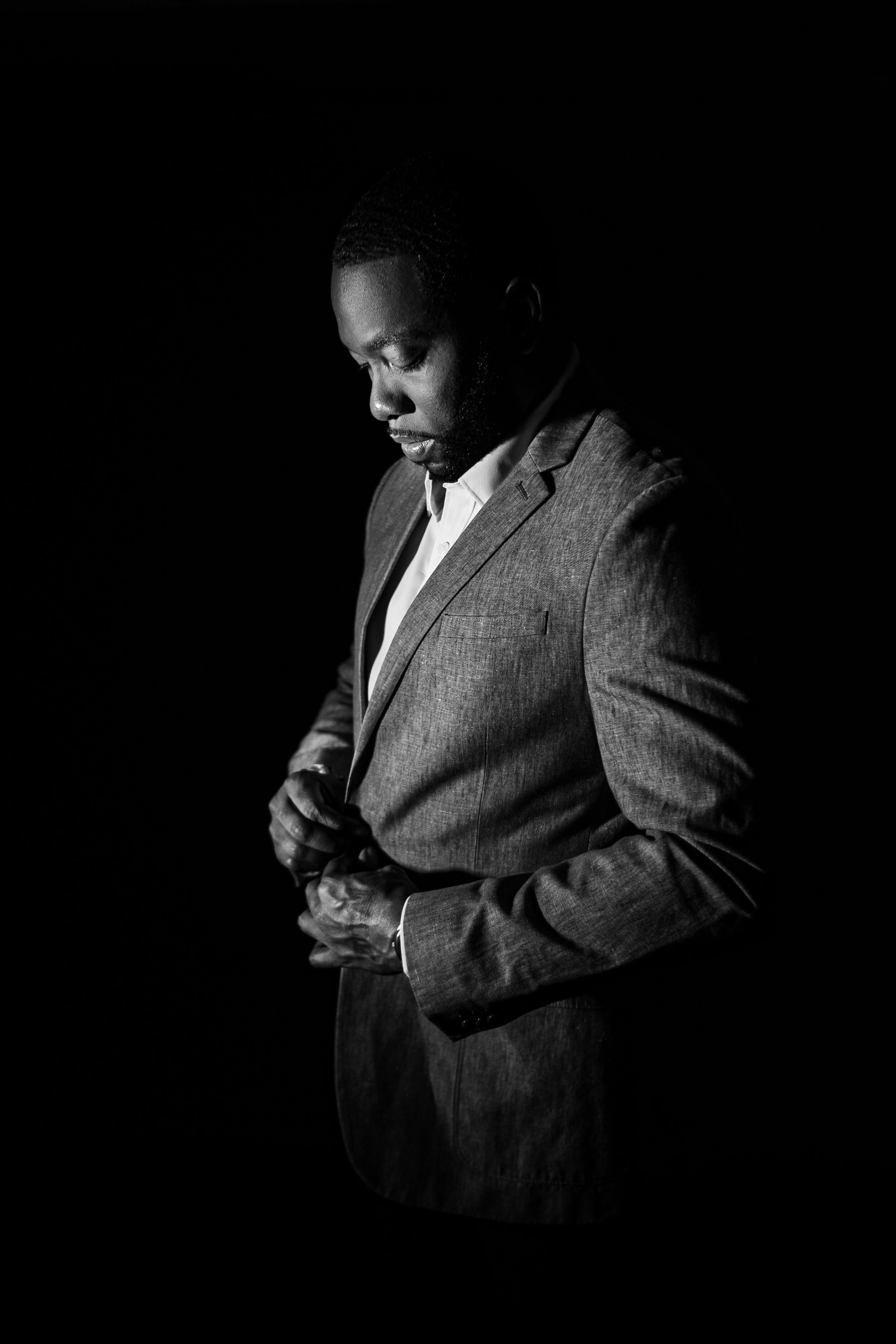 A man in a suit and tie is adjusting his jacket in a black and white photo.
