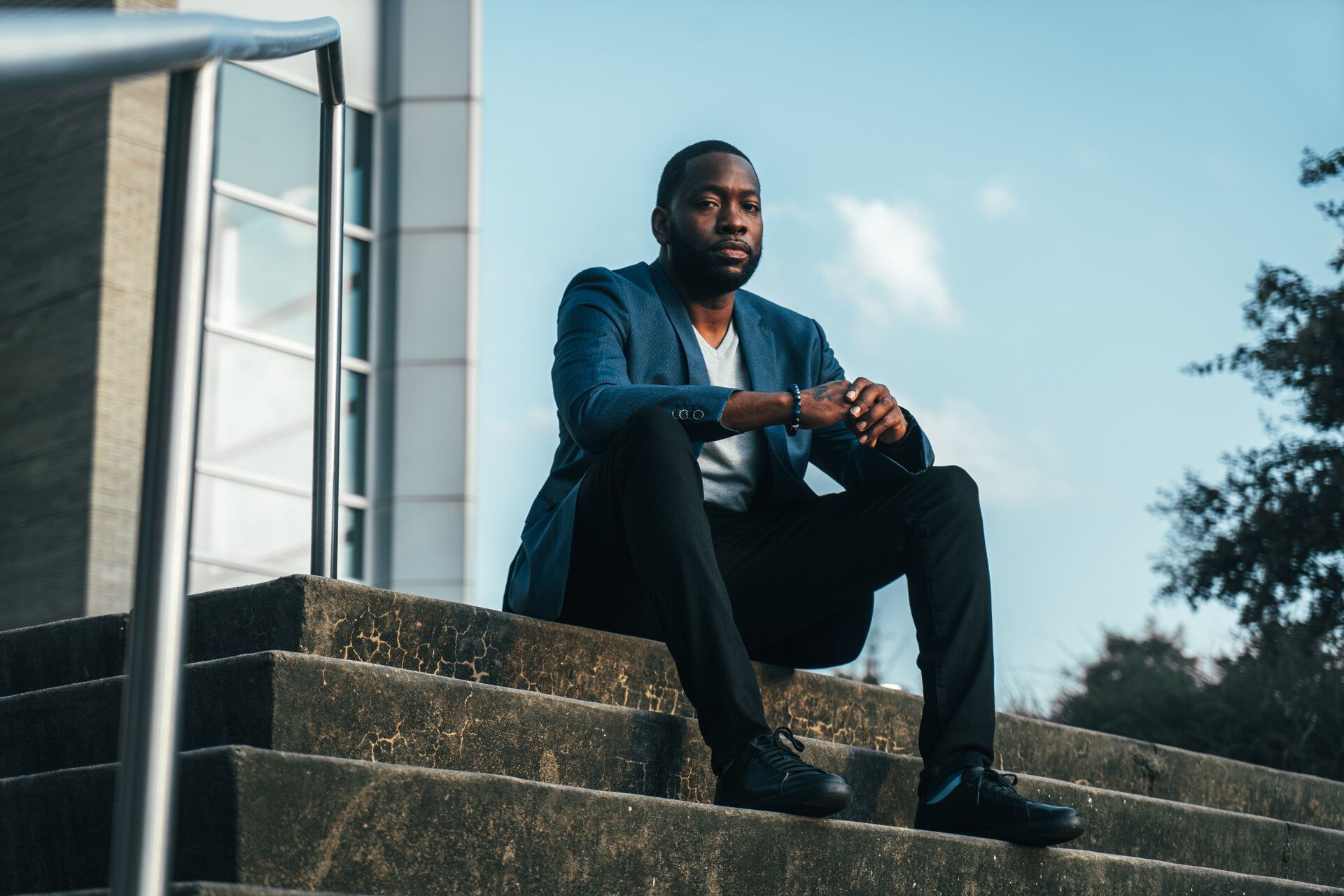 A man in a suit is sitting on the steps of a building.