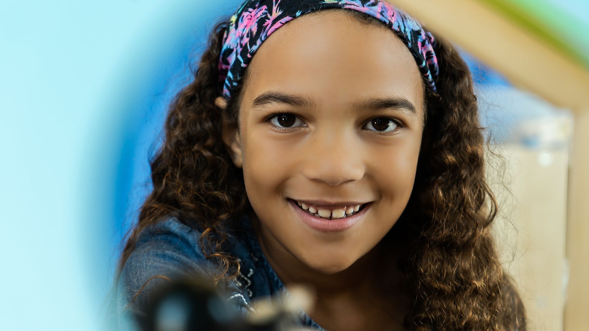 A young girl wearing a headband is smiling for the camera.