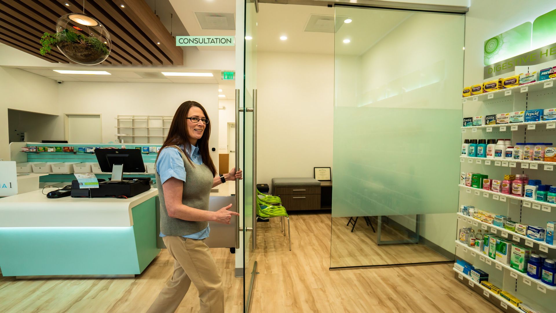 A woman is walking through a glass door in a pharmacy.
