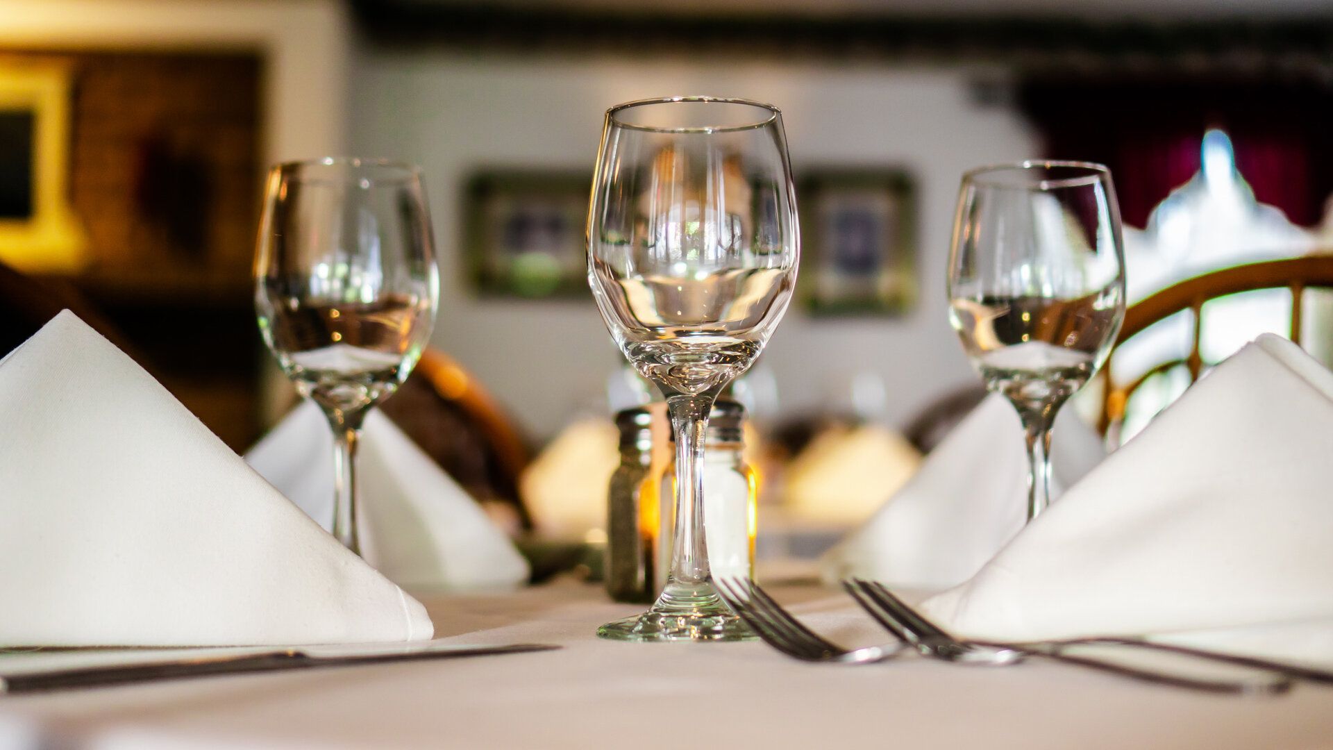 A table is set with wine glasses , silverware , and napkins.