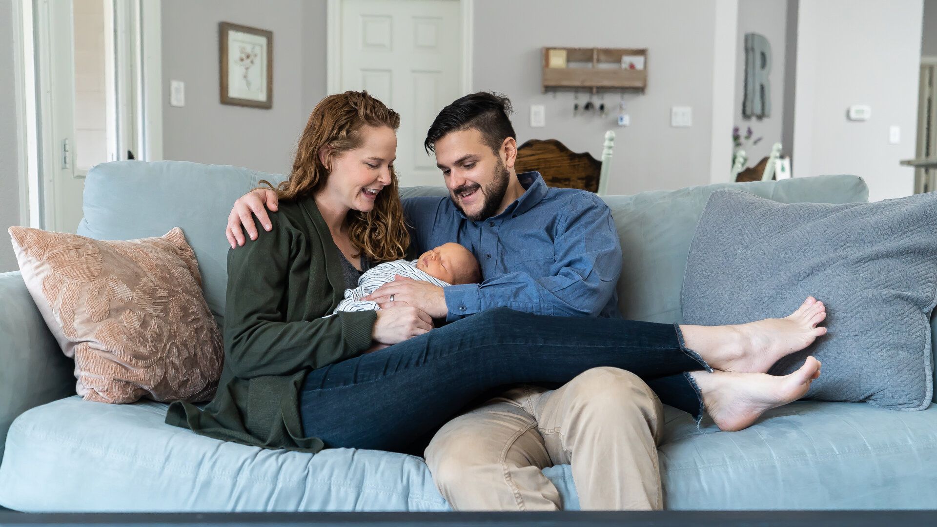 A man and woman are sitting on a couch holding a baby.