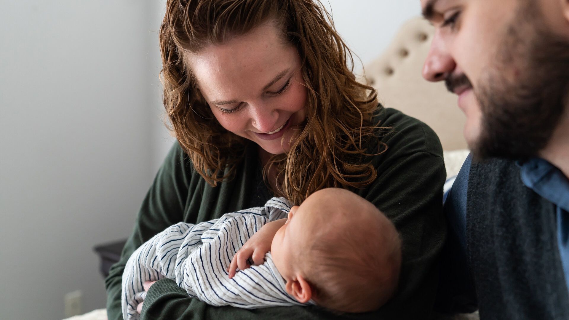 A woman is holding a baby while a man looks on.