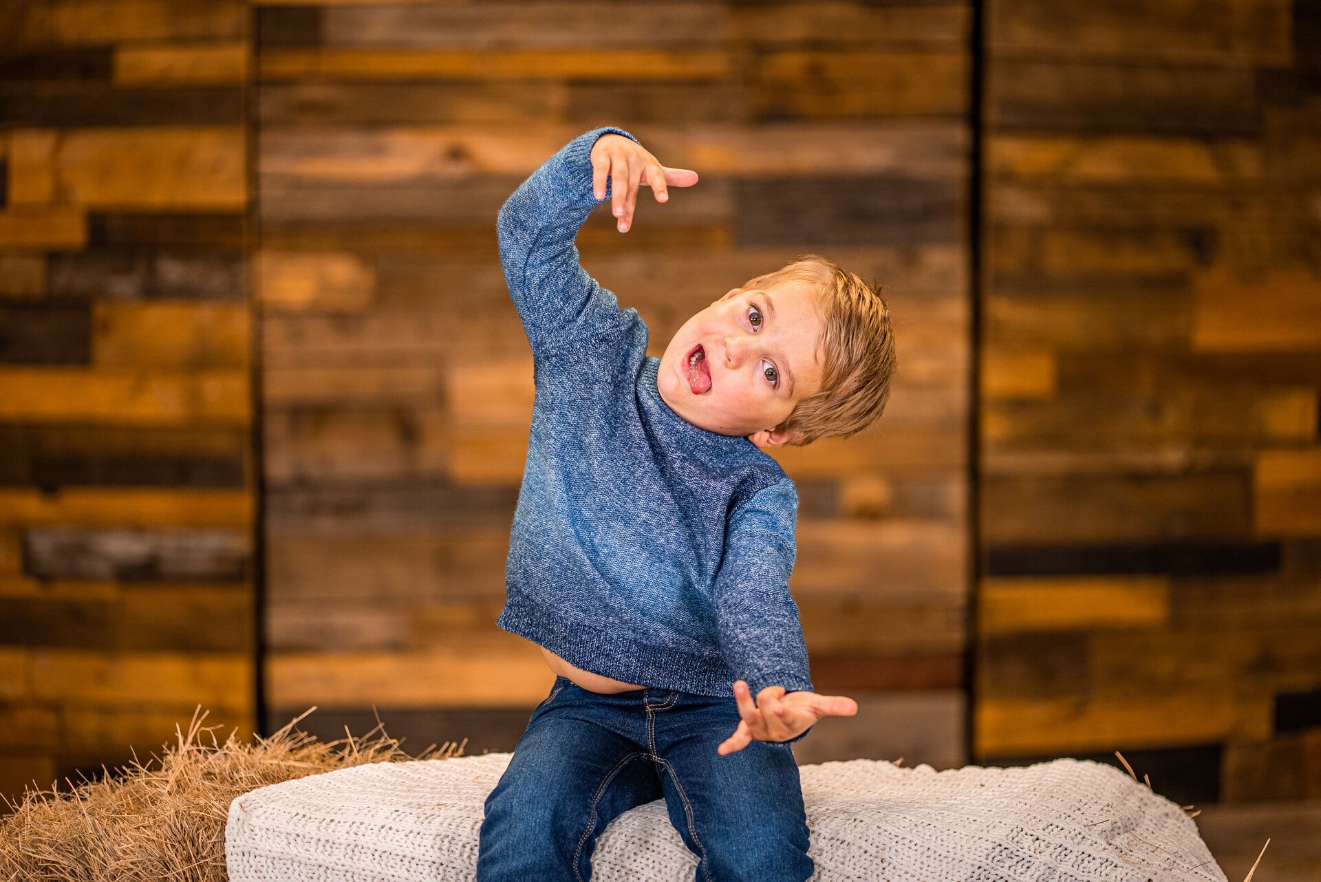 A young boy is sitting on a rock making a funny face.