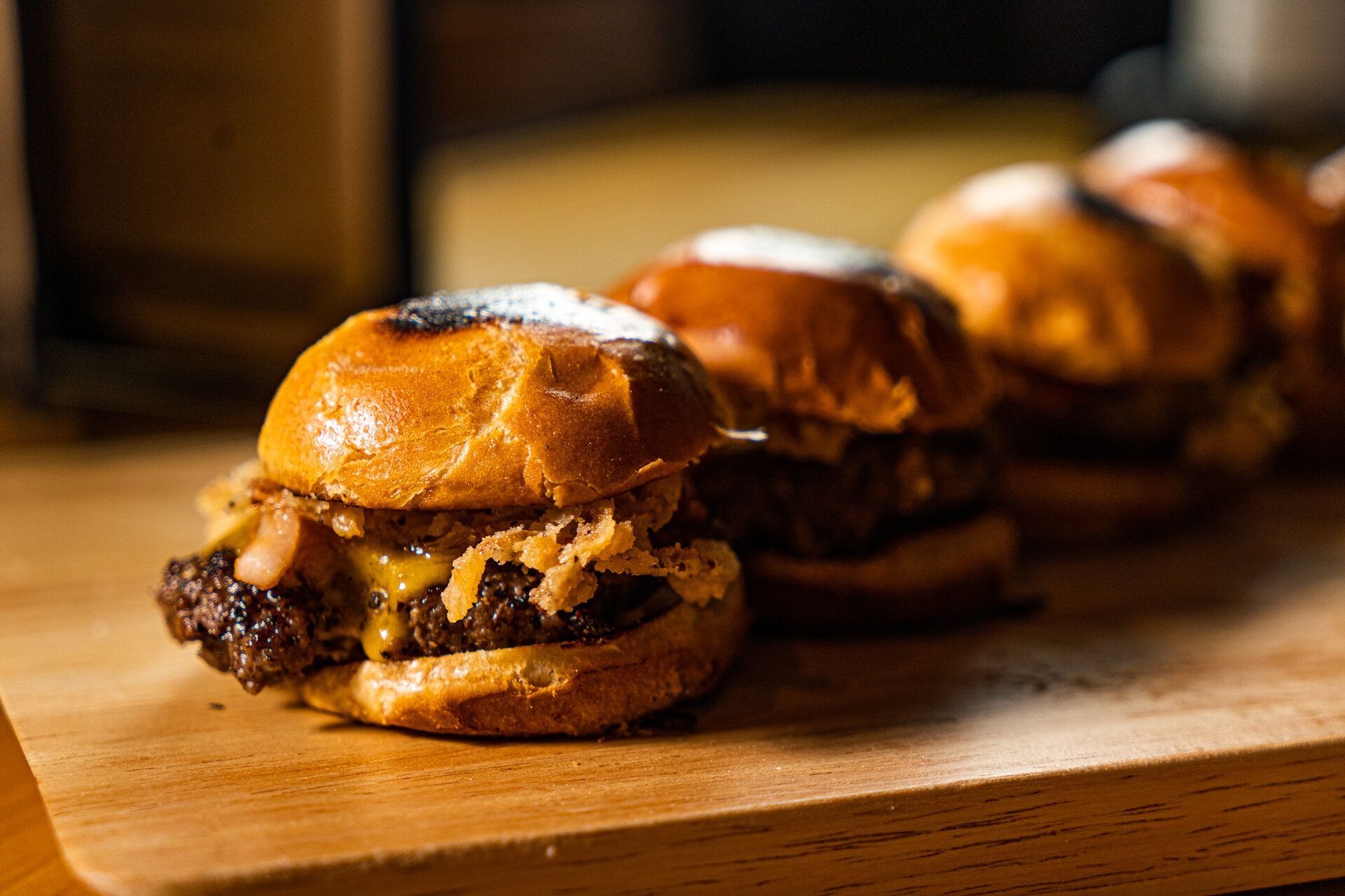 A row of sliders sitting on top of a wooden cutting board.