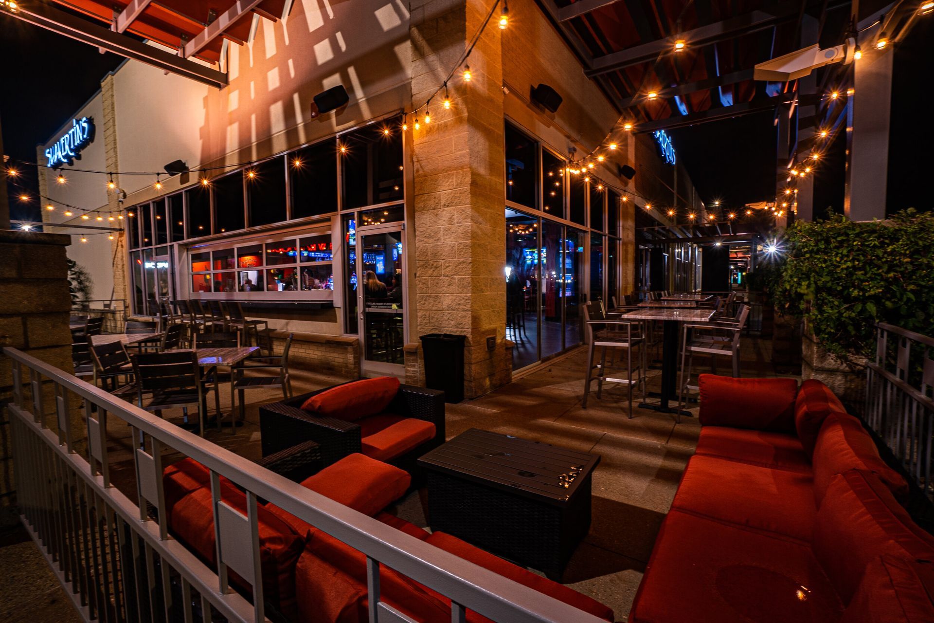 A restaurant with a patio area with red couches and tables.