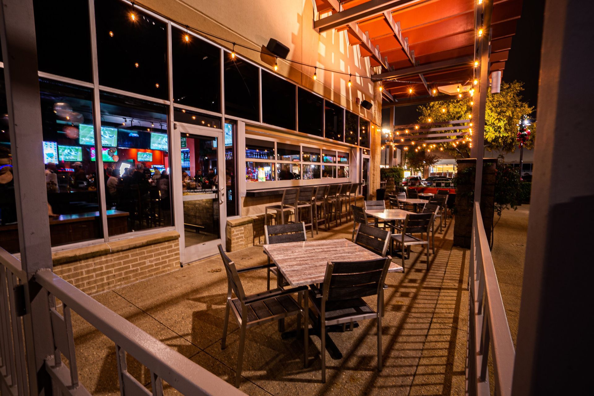 A restaurant with tables and chairs outside at night.