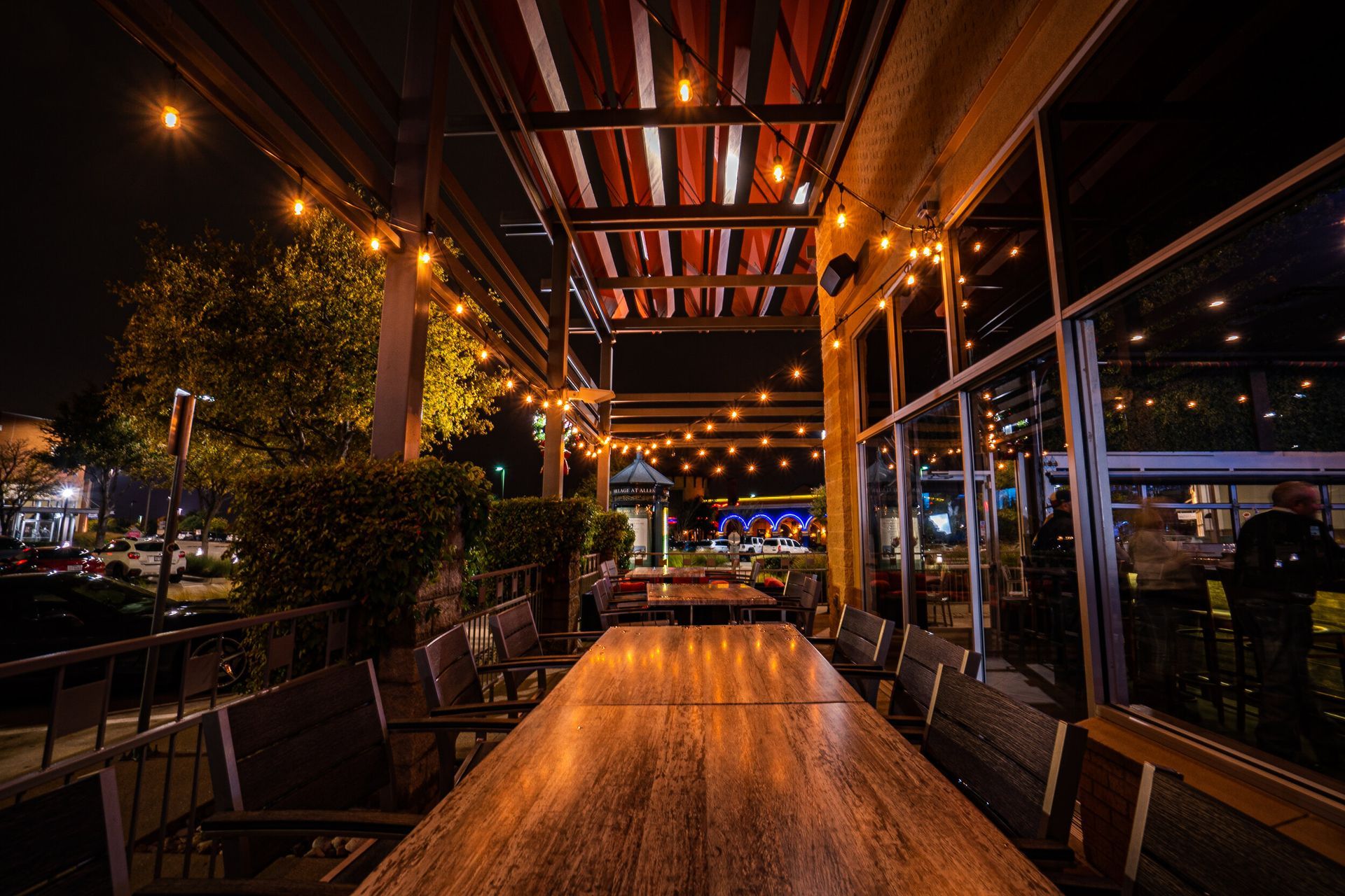 A long wooden table with chairs in a restaurant at night.
