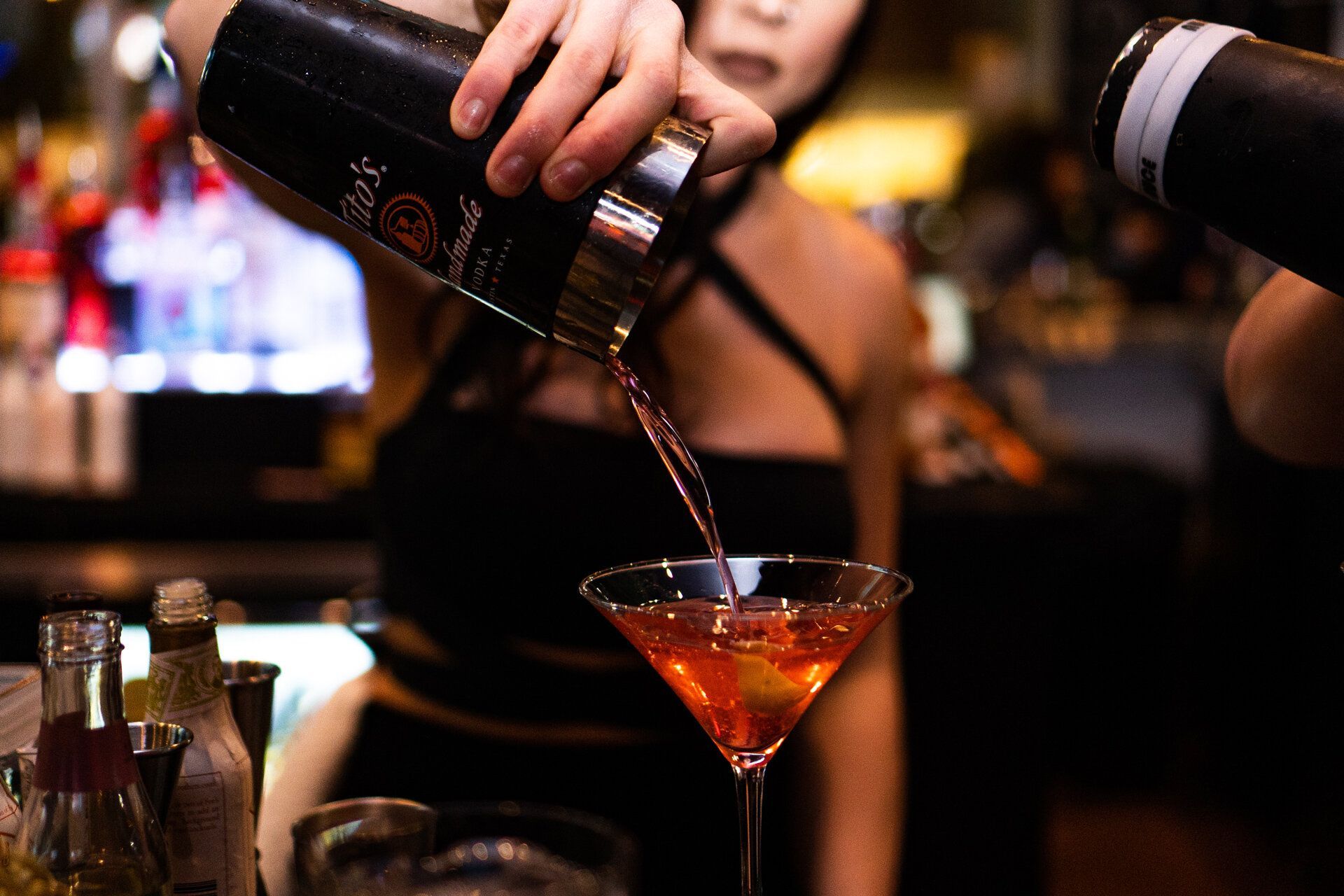 A woman is pouring a drink into a martini glass.