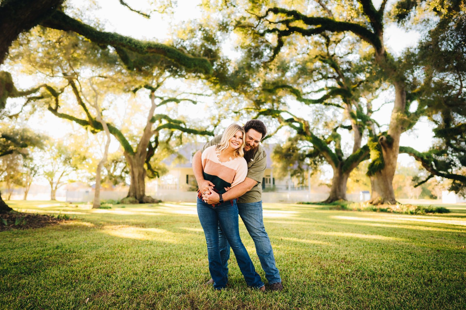 A man and a woman are hugging each other in a park.