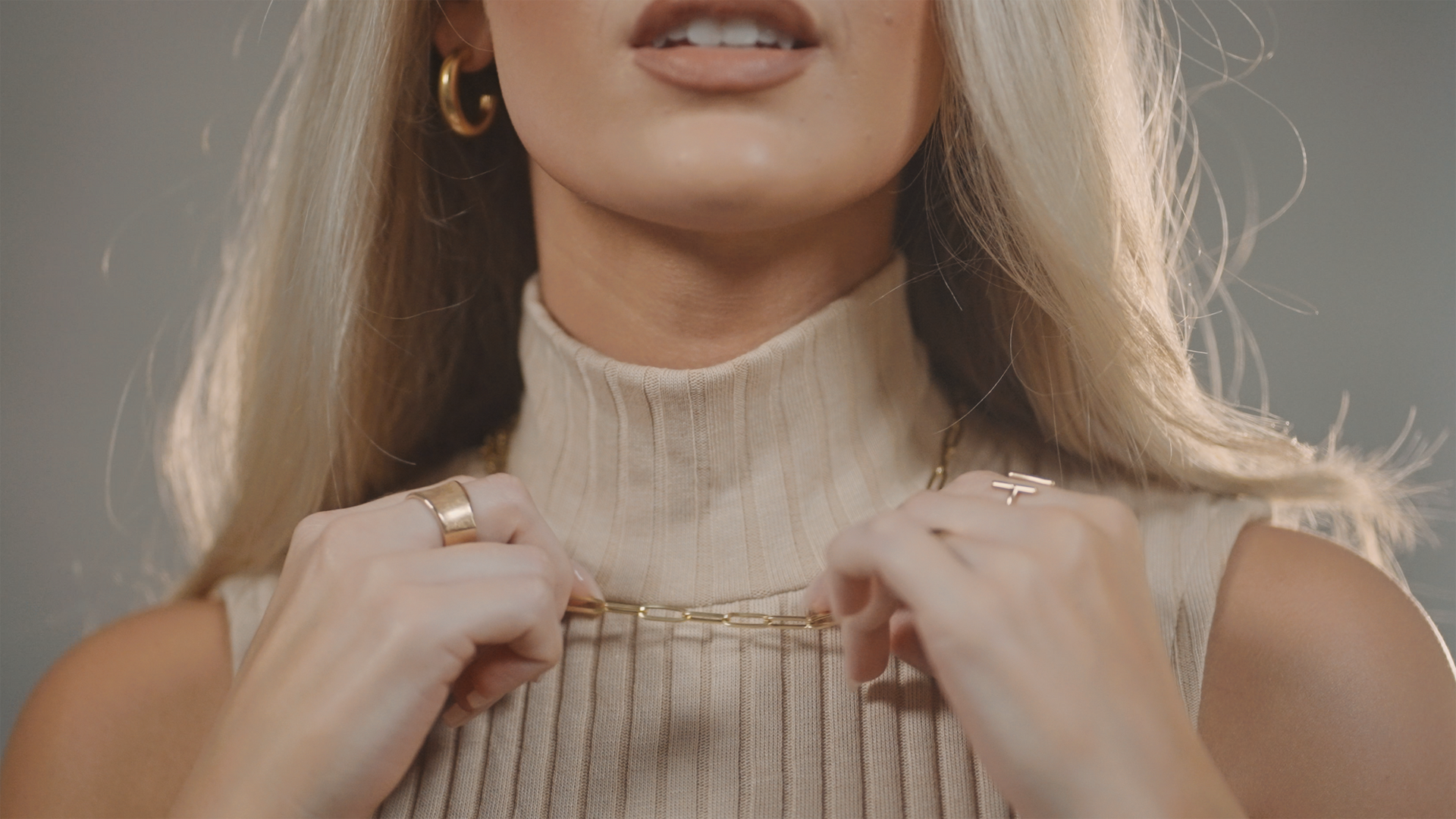 A close up of a woman wearing a turtleneck sweater and earrings.