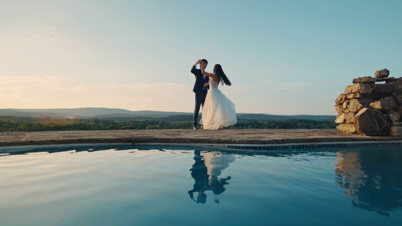 A bride and groom are walking down a dirt road holding hands.