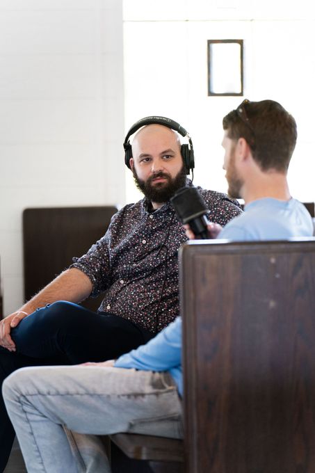 A man wearing headphones is sitting next to another man holding a microphone.