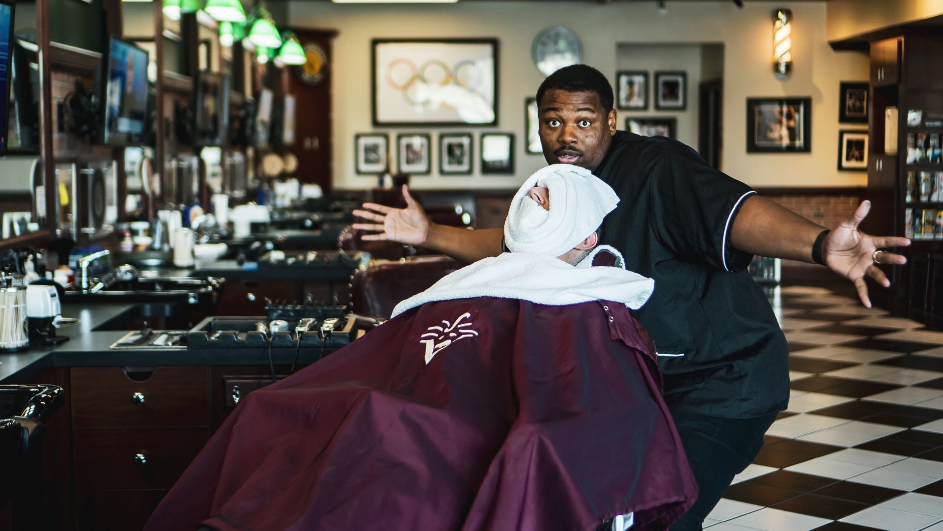 A man is shaving another man in a barber shop.