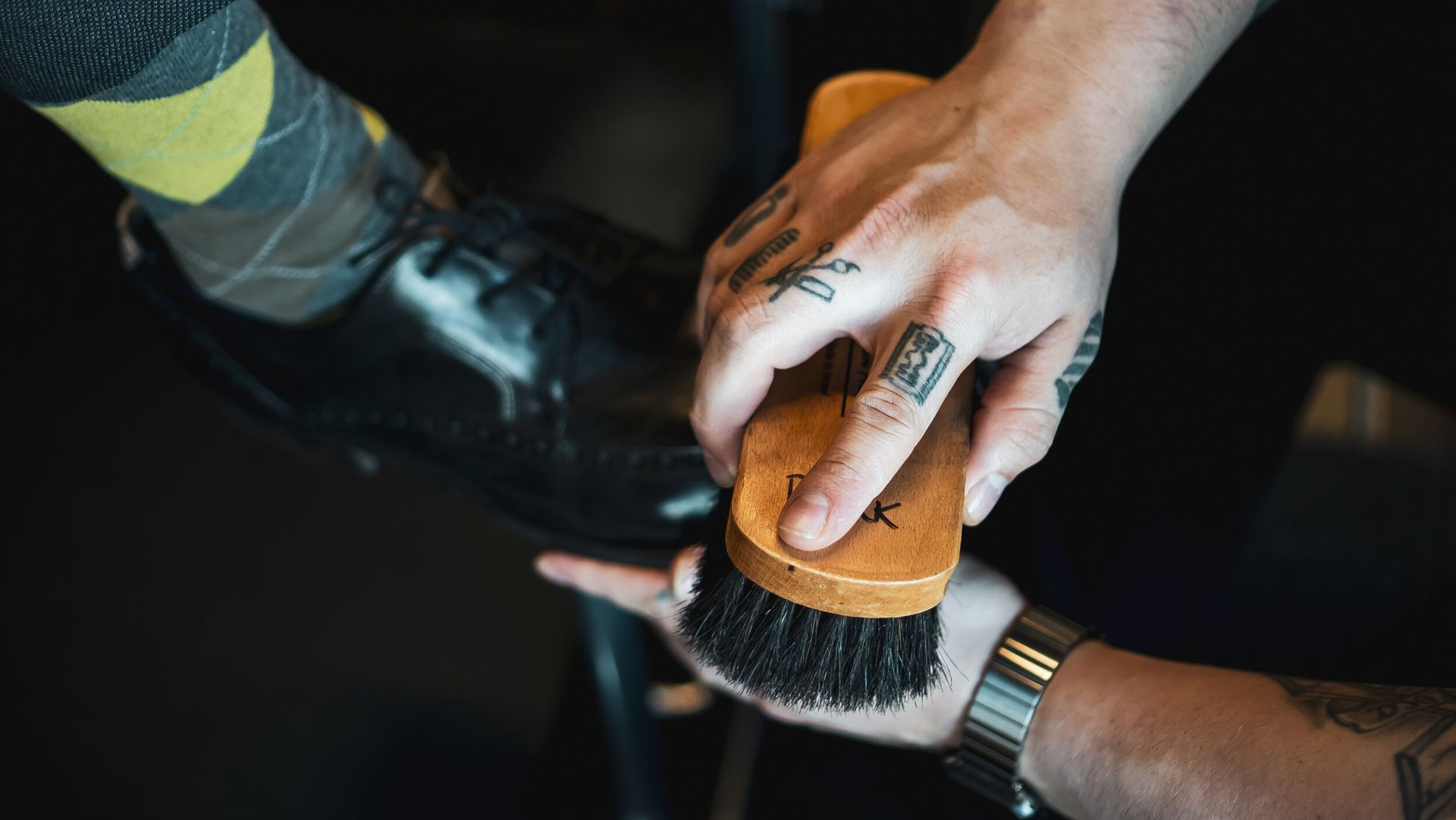 A person is polishing a pair of shoes with a brush.
