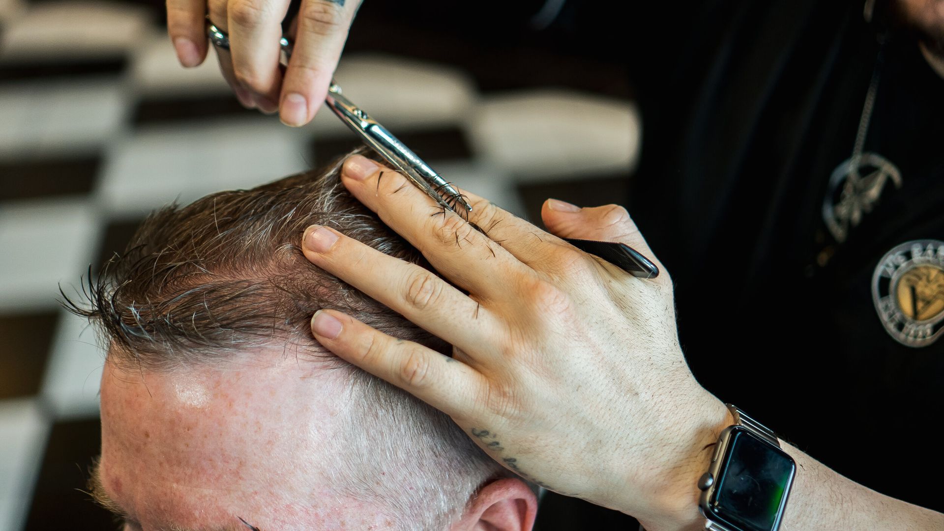 A man is getting his hair cut by a barber in a barber shop.