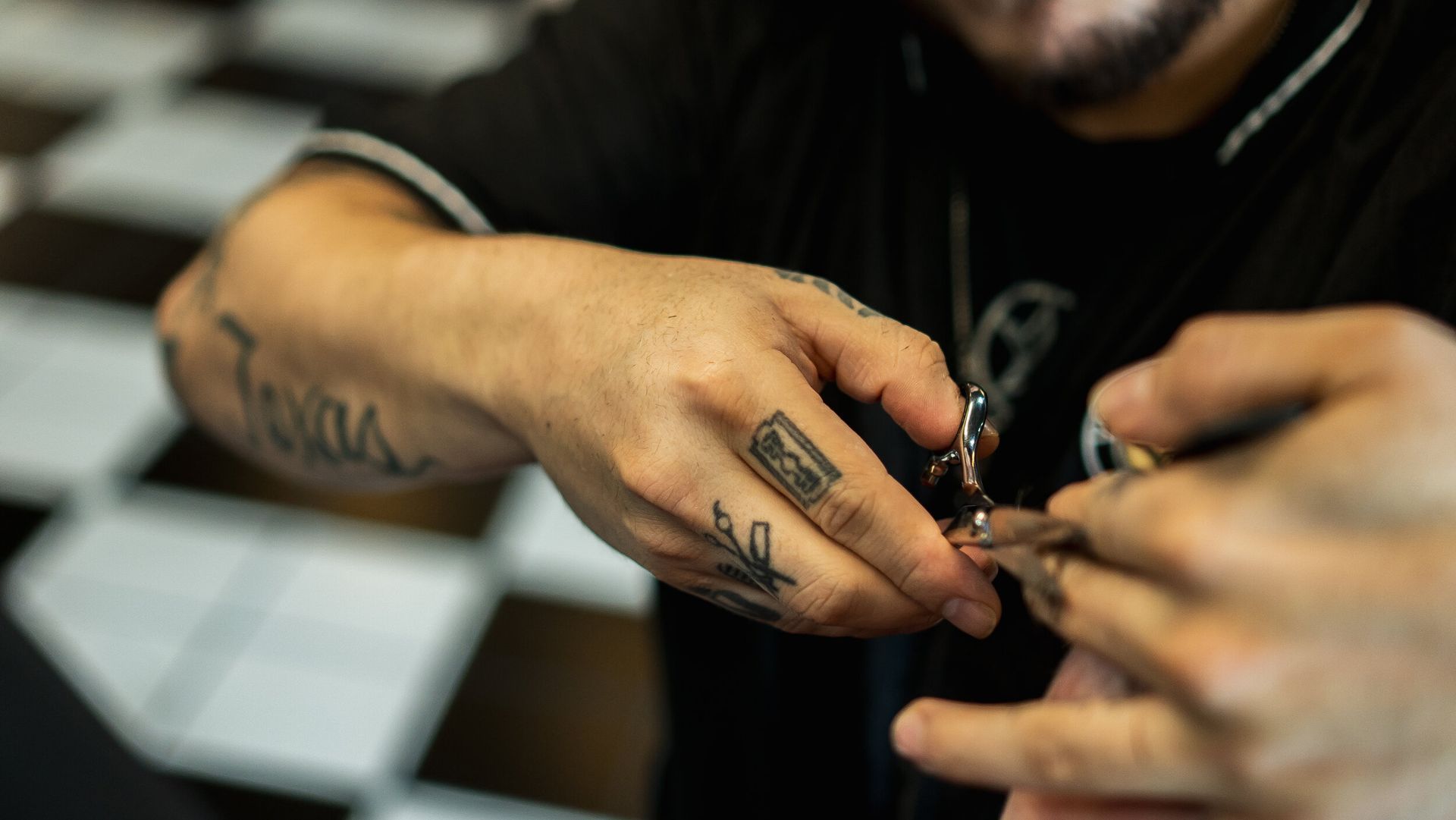 A man with tattoos on his hands is holding a pair of scissors.