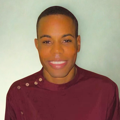 Smiling Black man in a maroon shirt, buttons on the shoulder, against a pale green background.