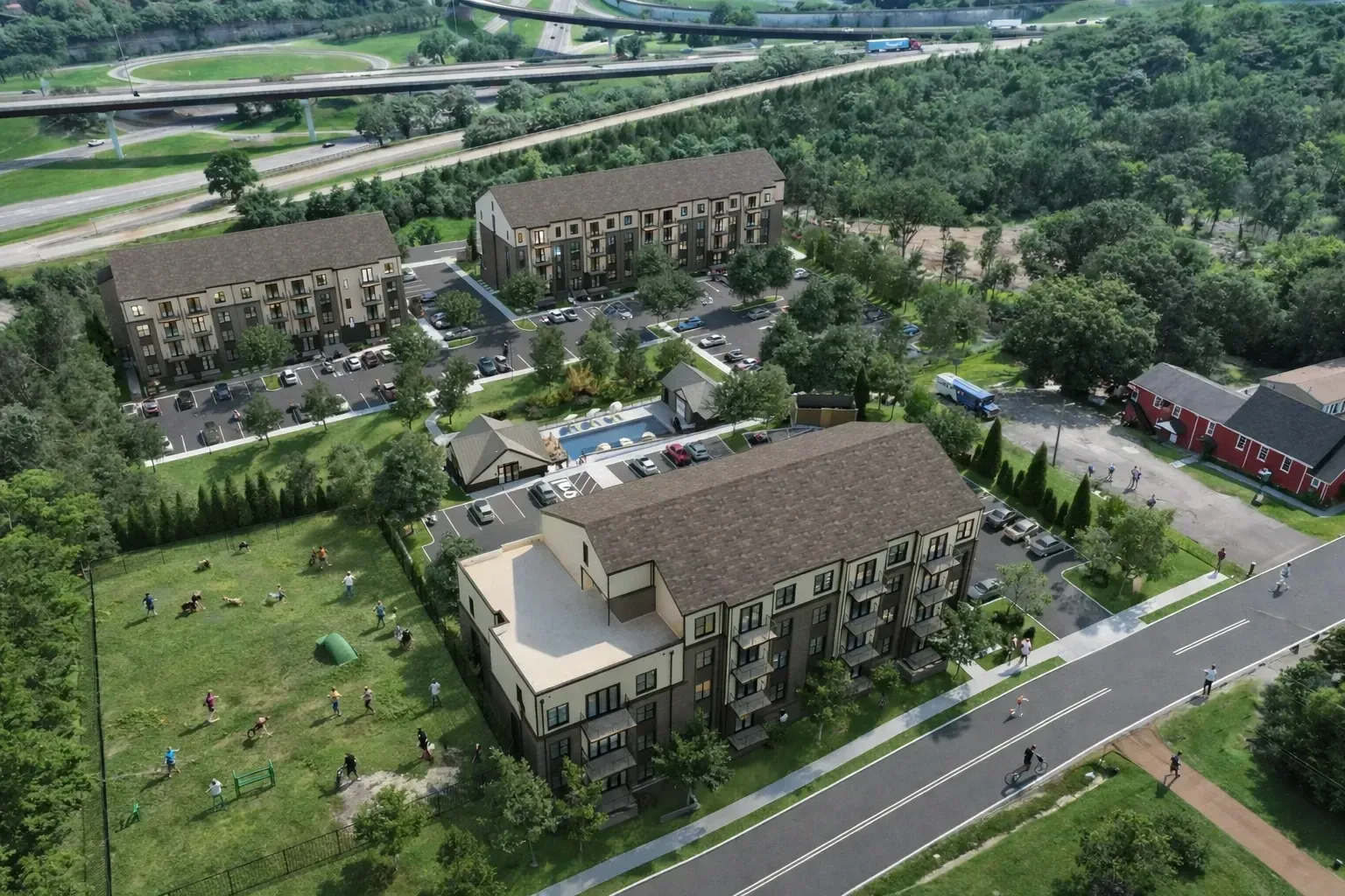 Aerial view of modern apartment buildings, parking lots, and green lawns beside a road and trees