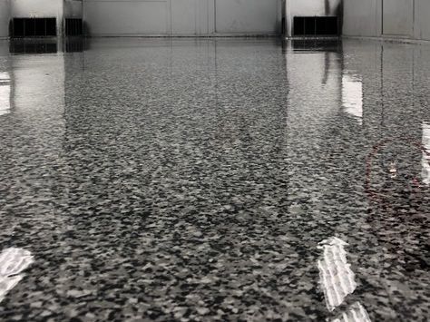 A glossy, grey-and-white speckled epoxy floor reflects light in a clean, modern room with wall-mounted vents.