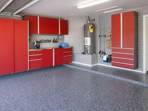 A modern garage featuring bright red storage cabinets, a gray slat wall, and a speckled epoxy floor.