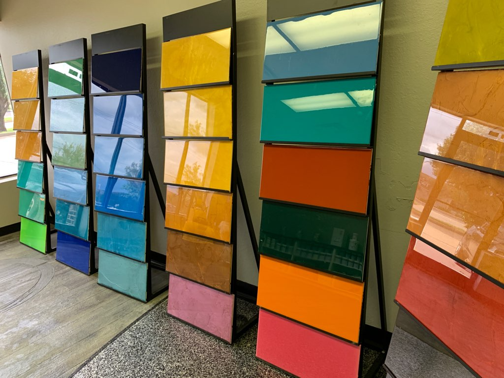 Display racks featuring colorful, rectangular, glossy glass or tile samples in various hues and textures.