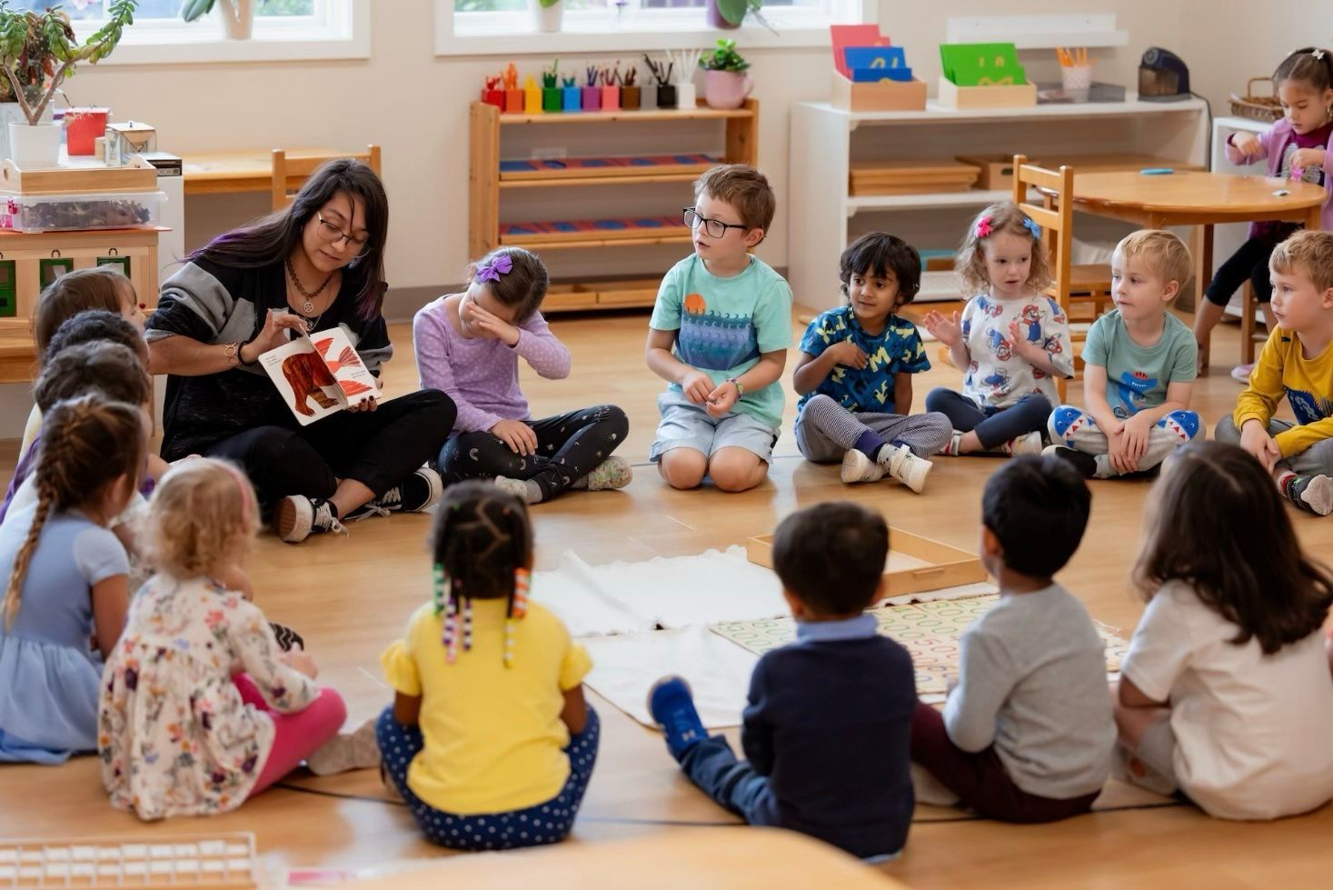 Teacher reading to a seated group of children in a bright classroom