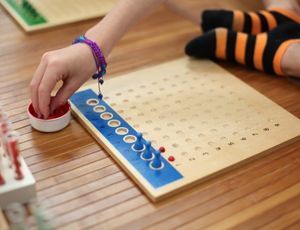 Child using Montessori bead board to learn multiplication and explore number patterns hands-on.