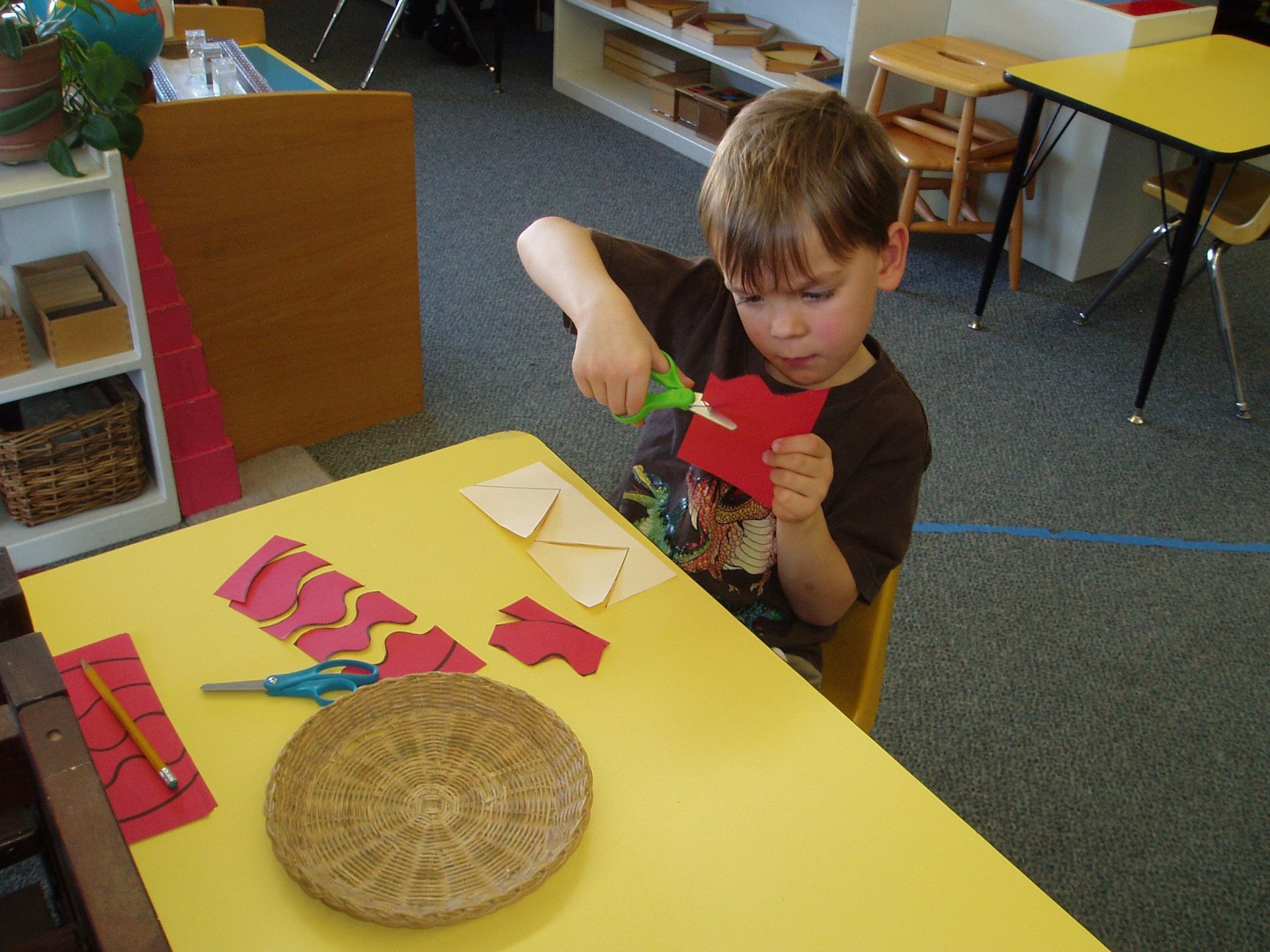 a young boy is cutting a piece of paper with scissors