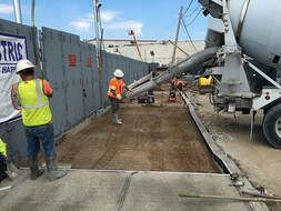 A concrete truck is pouring concrete on a construction site.