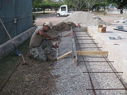 A man is kneeling down while working on a construction site.