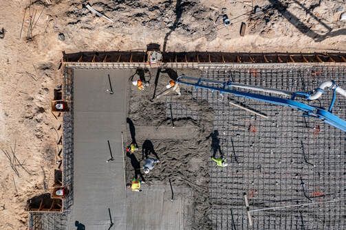 An aerial view of a construction site with workers pouring concrete.