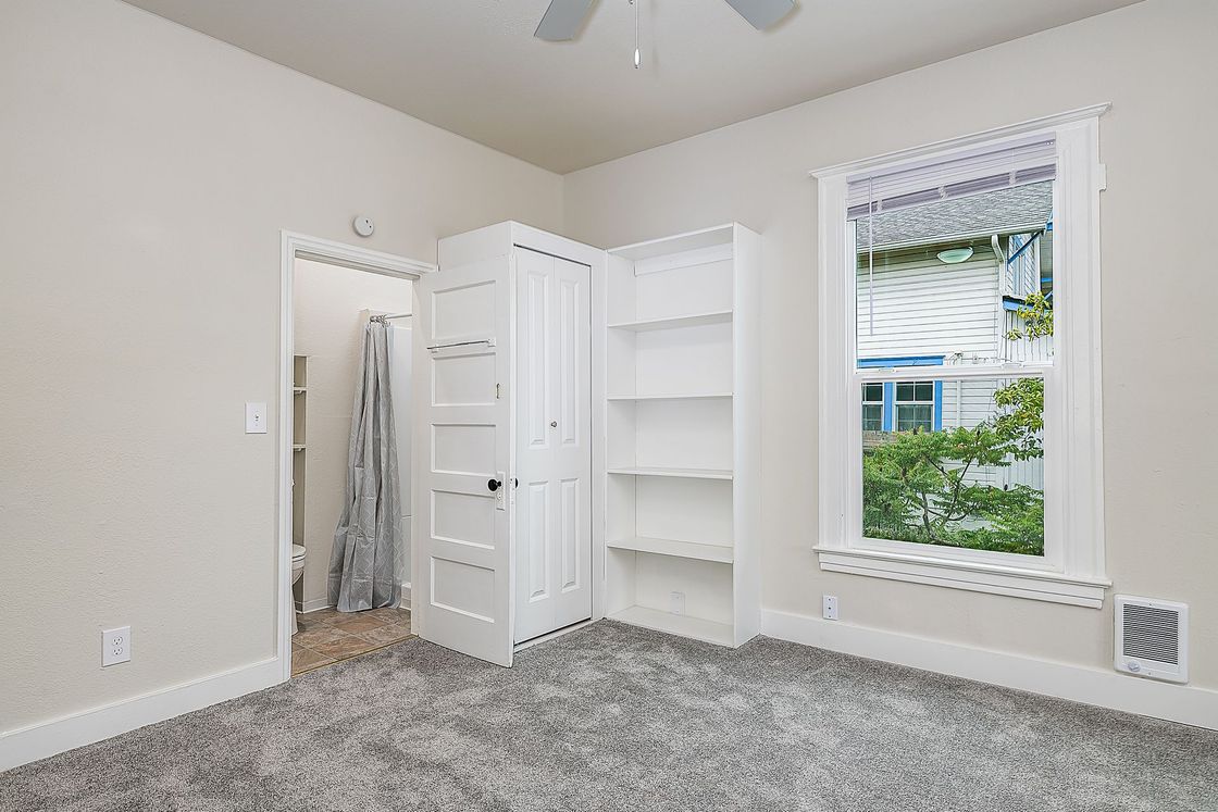 Photo of a room with a walk-in closet and tall window, as well as shelving