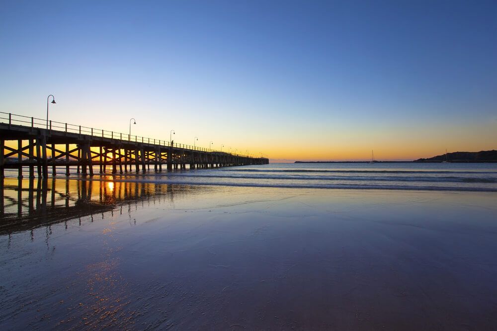 A Pier Overlooking A Body Of Water At Sunset — Coastal Plumbing Group in Coofs Harbour, NSW