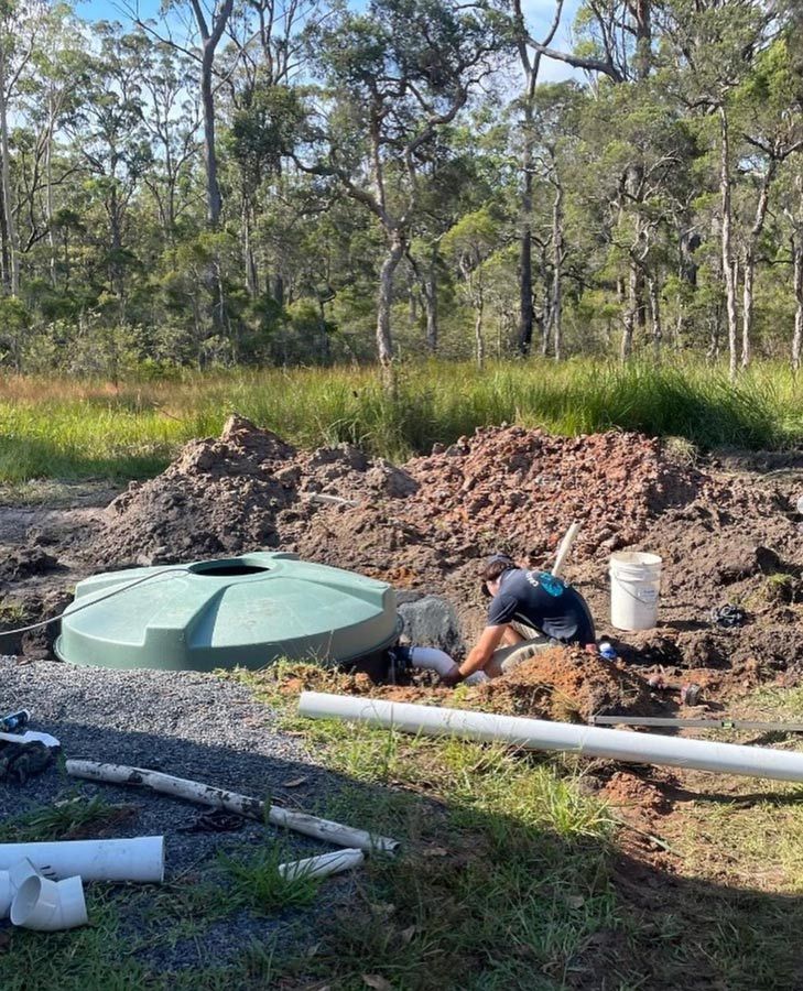 A Man Is Working On A Septic Tank In The Dirt — Coastal Plumbing Group in Woolgoolga, NSW
