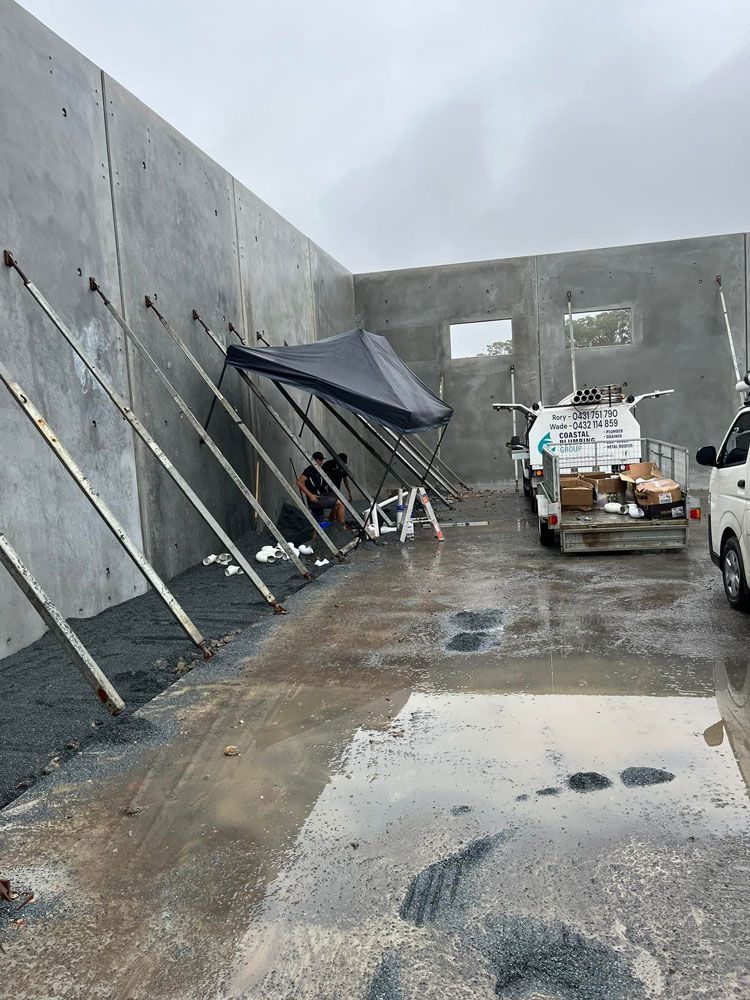 A Truck Is Parked In Front Of A Building Under Construction — Coastal Plumbing Group in Woolgoolga, NSW