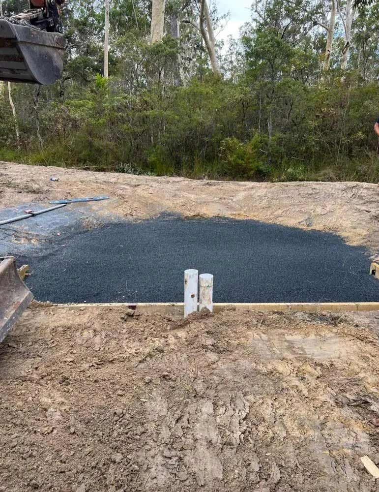 A Bulldozer Is Digging A Hole In The Dirt — Coastal Plumbing Group in Woolgoolga, NSW